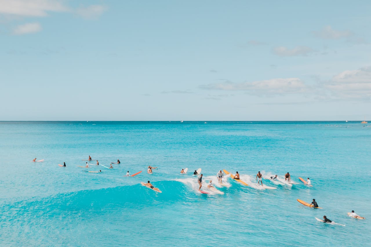 A vibrant scene of surfers enjoying the ocean under a clear sky, showcasing a beautiful summer day.
